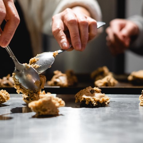 person-holds-spoons-to-portion-cookie-dough-to-cook
